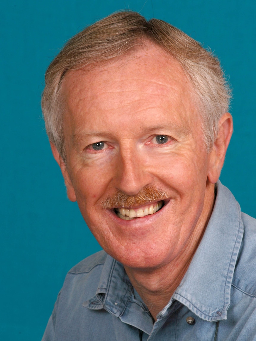 Image of a man in a blue shit against a blue background.