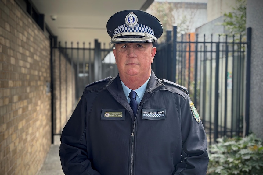 A police officer in uniform standing outside a police station