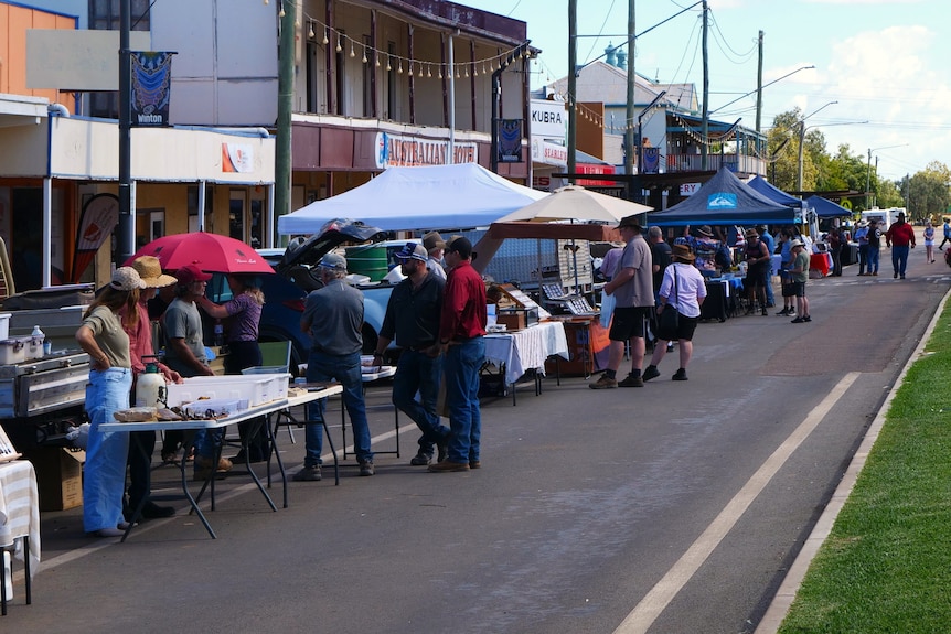 A marquees and folding tables out the front of shops on a main drag.