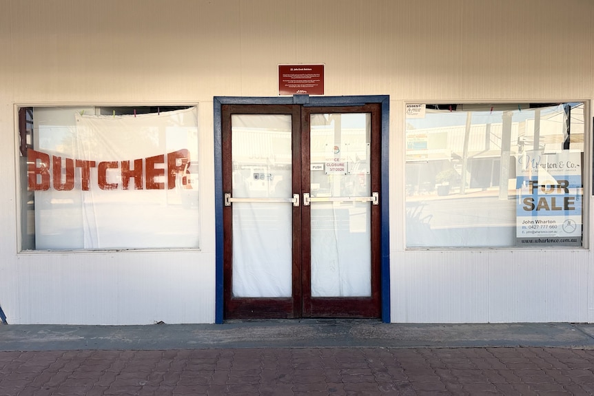 Julia Creek butcher with sheets over windows and for sale sign.