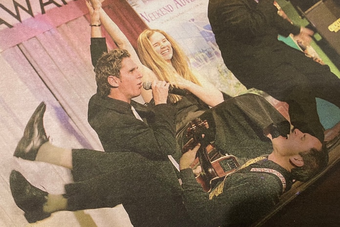Dale Alison when he was a younger musician, playing guitar on his back with his legs in the air.
