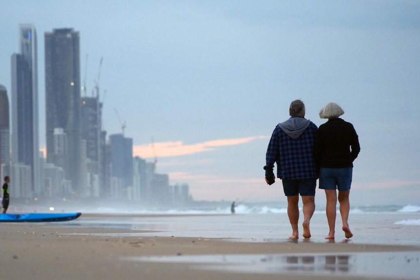 Two people walking on a beach at sunset