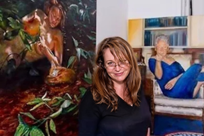 Woman smiles in front of portraits being exhibited