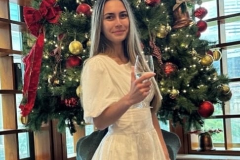 a woman standing in front of a christmas tree in a white dress