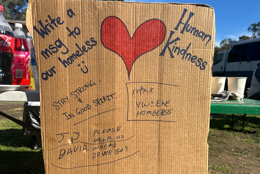 A piece of cardboard with well-wishes to homeless people written on it.