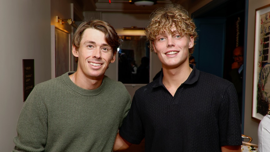 Alex de Minaur and Cruz Hewitt stand next to each other in casual clothing at a pre-tournament function. 