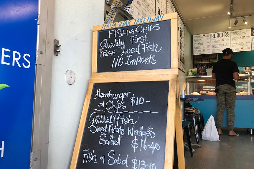 A blackboard in front of a takeaway shop announces 'no imports', only 'fresh local fish' on menu