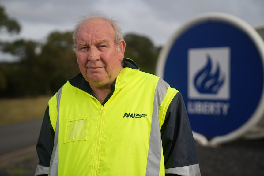 An older, balding man in a yellow hi-vis vest.