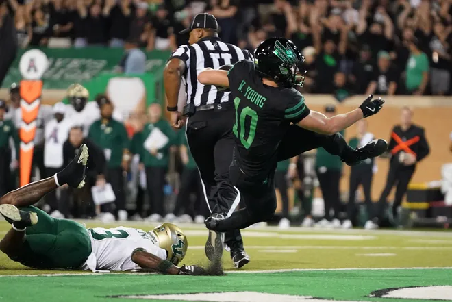 Oct 10, 2025; Denton, Texas, USA; North Texas Mean Green wide receiver Wyatt Young (10) carries the ball for a touchdown as South Florida Bulls cornerback Jonas Duclona (3)defends during the first half of a game at DATCU Stadium. Mandatory Credit: Raymond Carlin III-Imagn Images