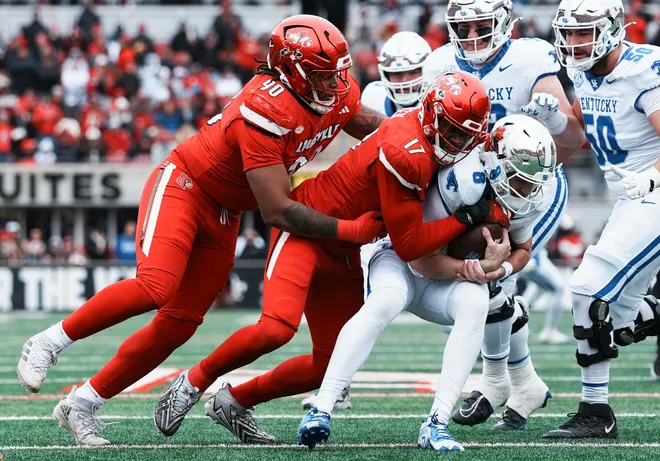 Louisville Cardinals defensive lineman AJ Green (17) grabs Kentucky Wildcats quarterback Cutter Boley (8) as Louisville Cardinals defensive lineman Clev Lubin (50) helps in the first half Saturday, November 29, 2025 in Louisville, Kentucky at L & N Federal Credit Union Stadium.