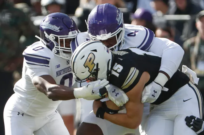 Northwestern Wildcats defensive back Coco Azema (0) and Northwestern Wildcats defensive lineman Anto Saka (4) tackle Purdue Boilermakers quarterback Ryan Browne (15) Saturday, Nov. 2, 2024, during the NCAA football game at Ross-Ade Stadium in West Lafayette, Ind.