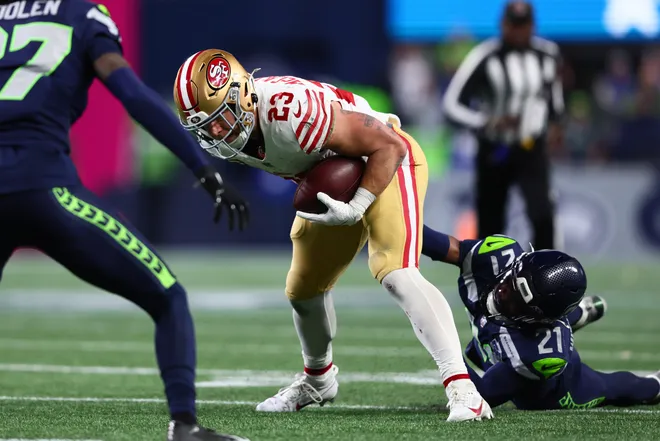 San Francisco 49ers running back Christian McCaffrey (23) carries the ball as Seattle Seahawks cornerback Devon Witherspoon (21) defends.