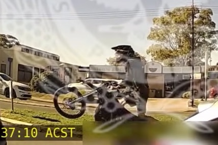A motorcycle rider doing a wheelie past commercial buildings