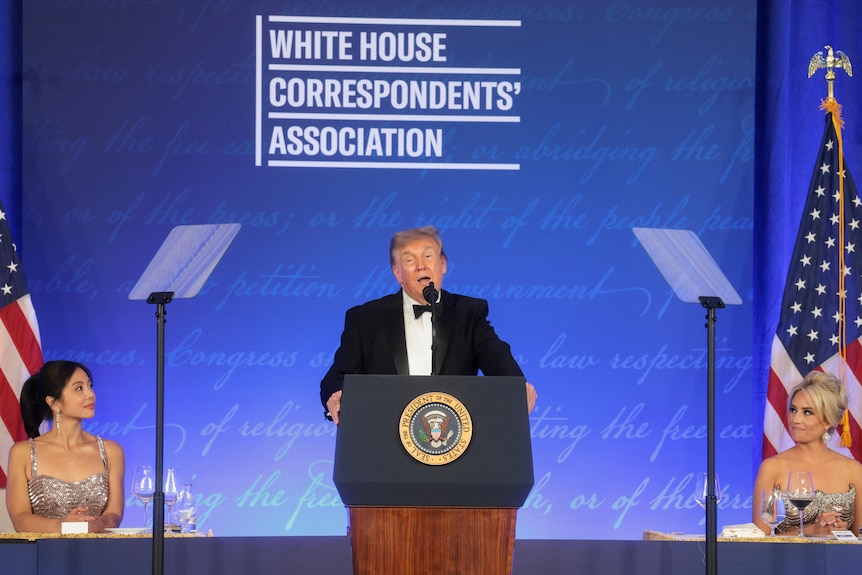Donald Trump, dressed in a tuxedo, speaks from a lectern in front of a White House Correspondents' Association backdrop.