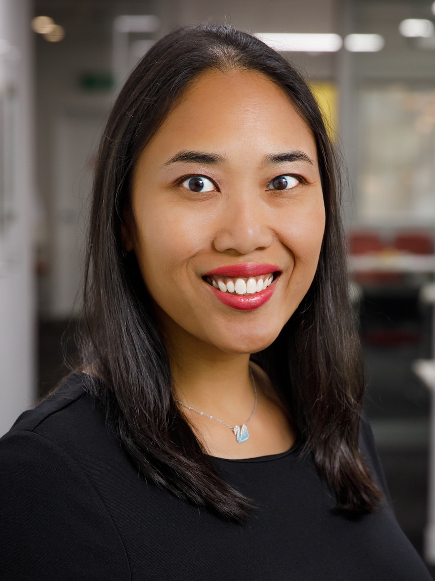 A young Indonesian woman smiles broadly while looking directly at the camera.smiling