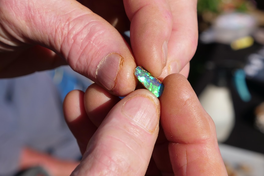 A piece of opal between a person's fingertips.