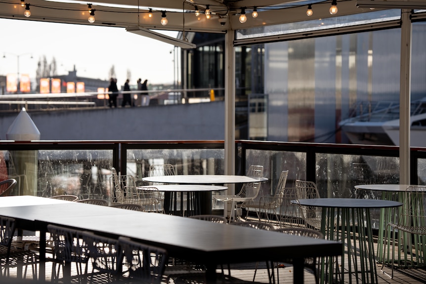 Tables and chairs on an undercover balcony looking out to buildings on the Hobart waterfront.