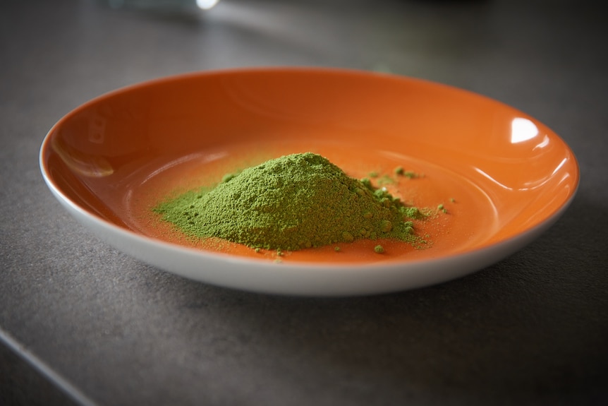 A mound of green powder in an orange bowl.