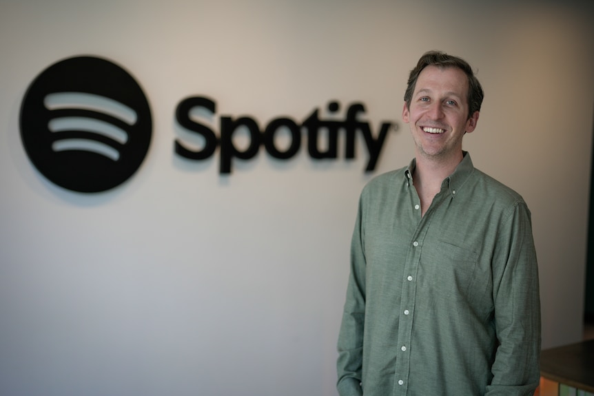 Sam Duboff wearing a green shirt standing in front of a Spotify sign.