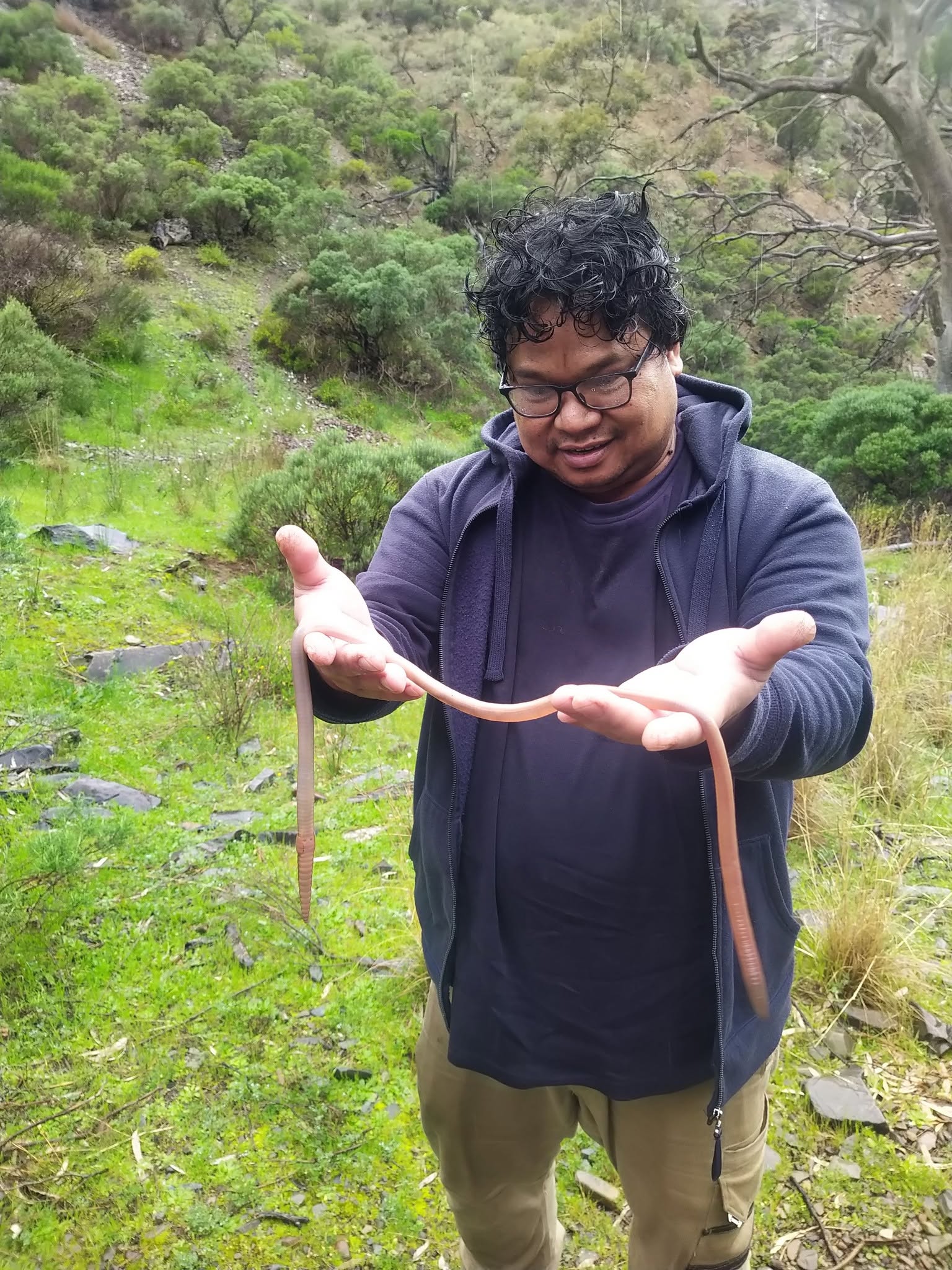 A man holding a very long earthworm
