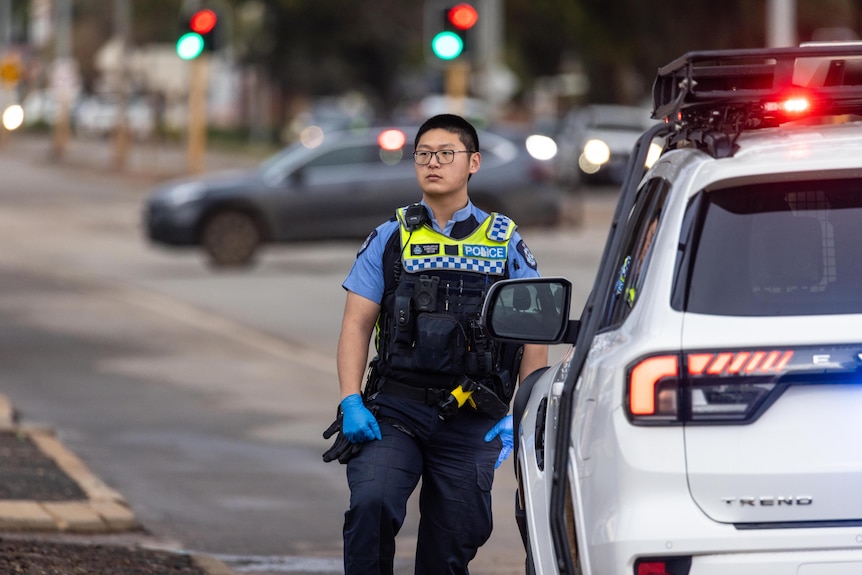 A police officer standing his post with street cordoned off.