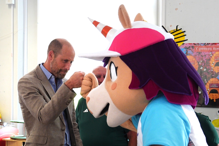 Prince William, Prince of Wales, fist bumps Finnie, a unicorn-themed Glasgow 2026 Commonwealth Games mascot.