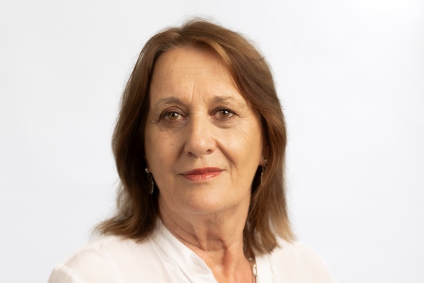 Barbara smiles while wearing a plain white button up shirt.
