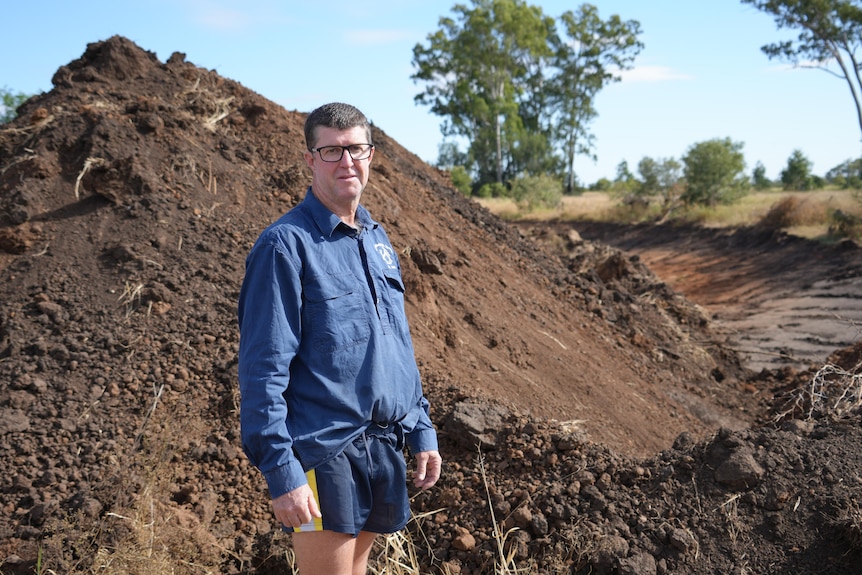 A man looking at the camera with a levy bank under construction in the background