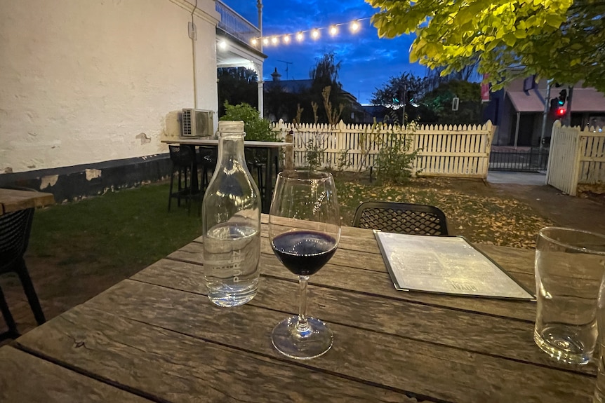 Generic red wine glass on wooden table in pub beer garden