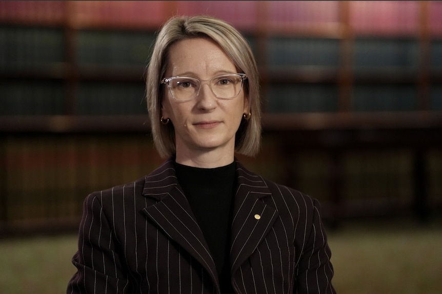 Woman with glasses and pinstripe suit stares at the camera