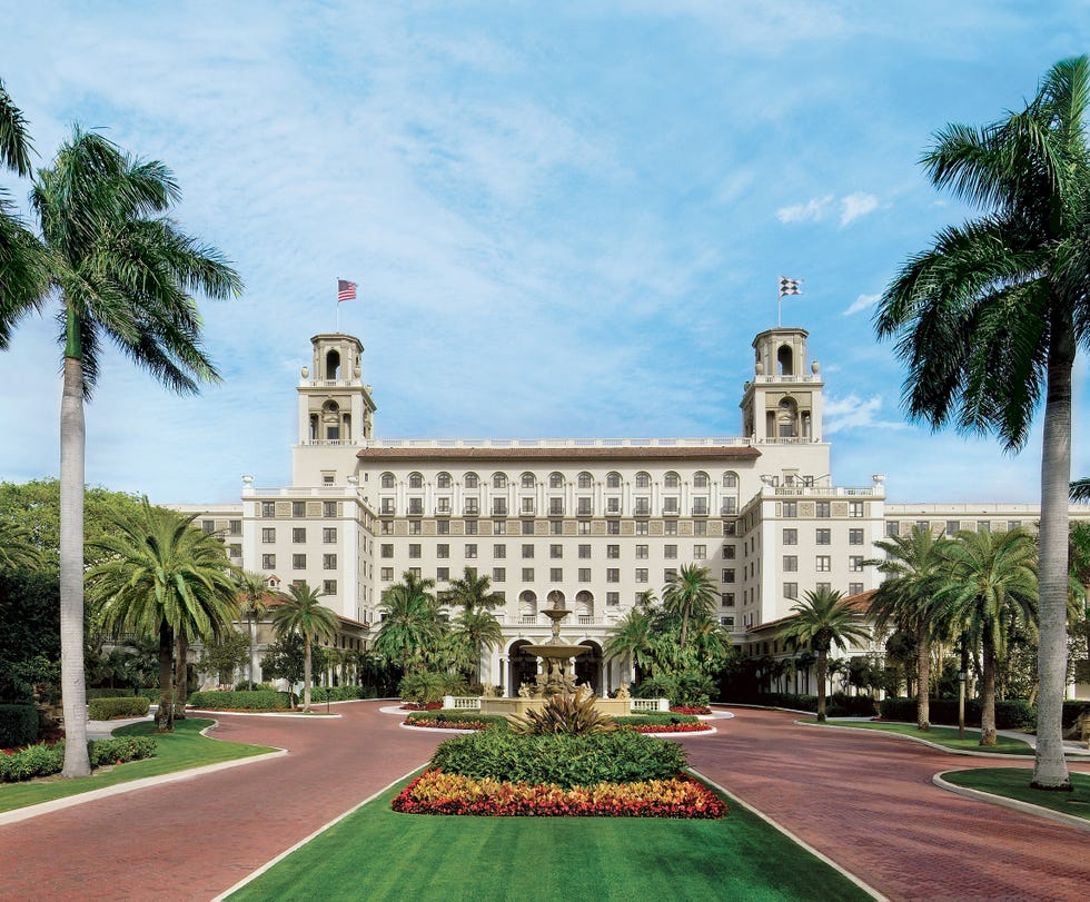 The Breakers Florida grand building with palm trees and red brick driveway under a clear blue sky.
