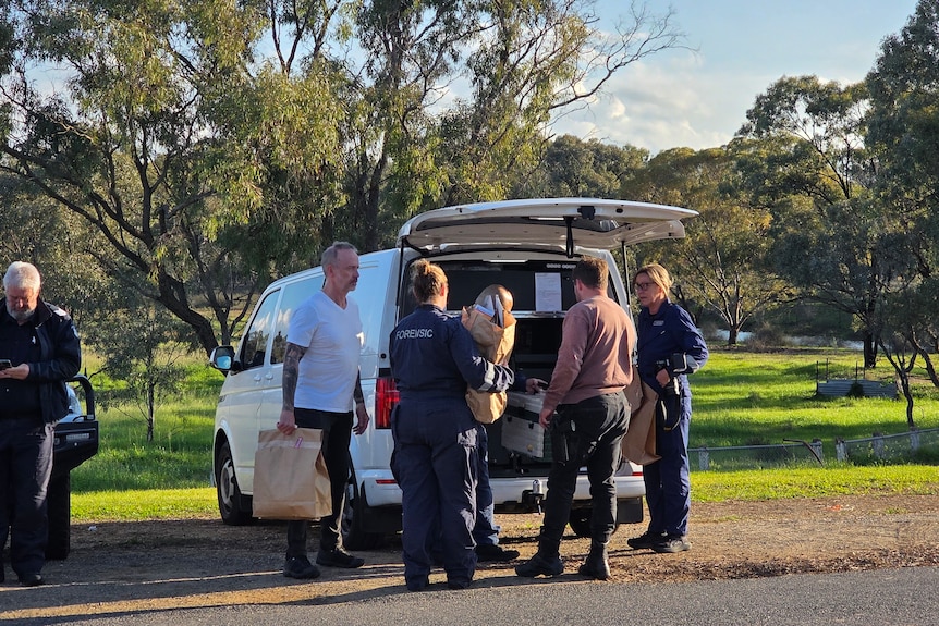 Police carry evidence bags near car