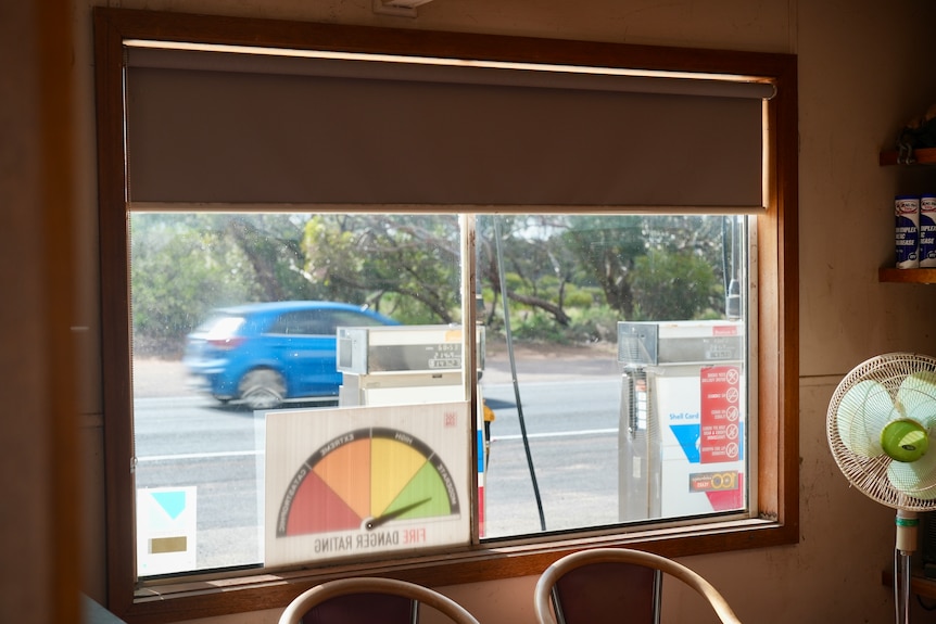 Blurry blue car pictured driving past, through window, taken from within old office building at mechanics, boswers outside