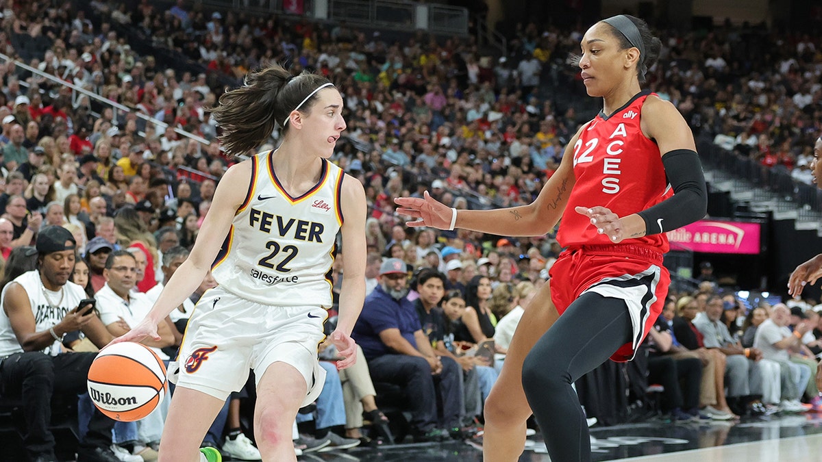 Caitlin Clark dribbles the basketball while being defended by A'ja Wilson.