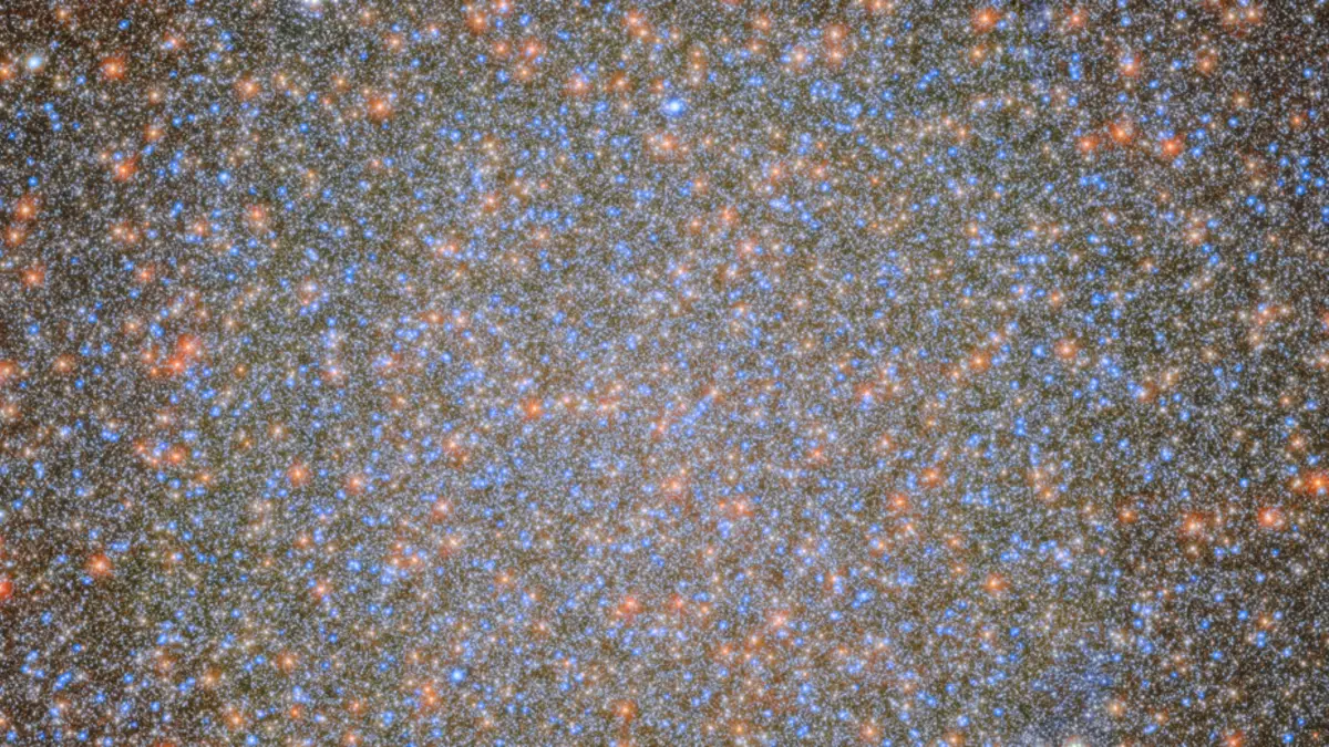 An image of the globular cluster Omega Centauri, a collection of myriad stars colored red, white, and blue on the black background of space