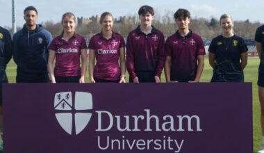 Members of the University Cricket Club and Durham Cricket Club standing with a Durham University purple banner.