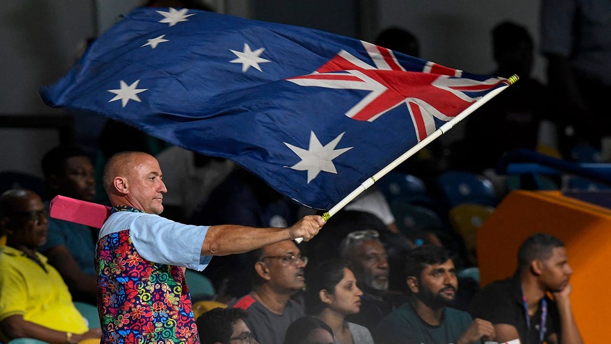 Supporter waves an Australia flag at a cricket match.