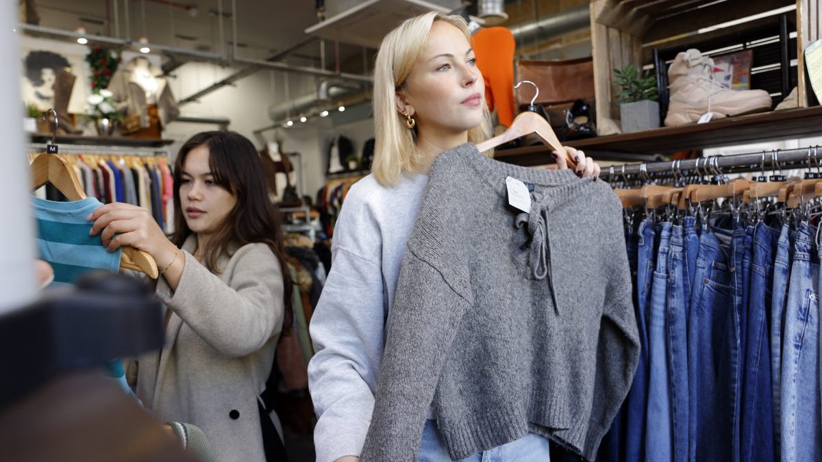 Two young women shopping in a vintage charity shop - stock photo