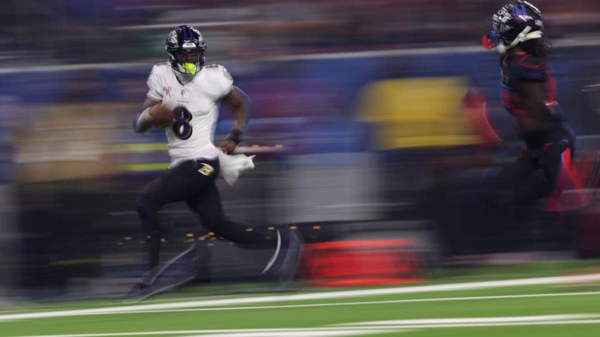 Lamar Jackson runs with the ball in a game at NRG Stadium.