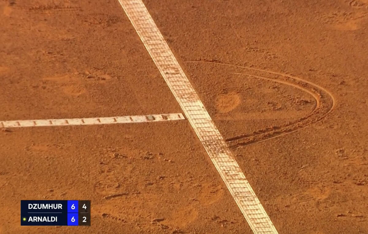 A ball mark on a clay tennis court.