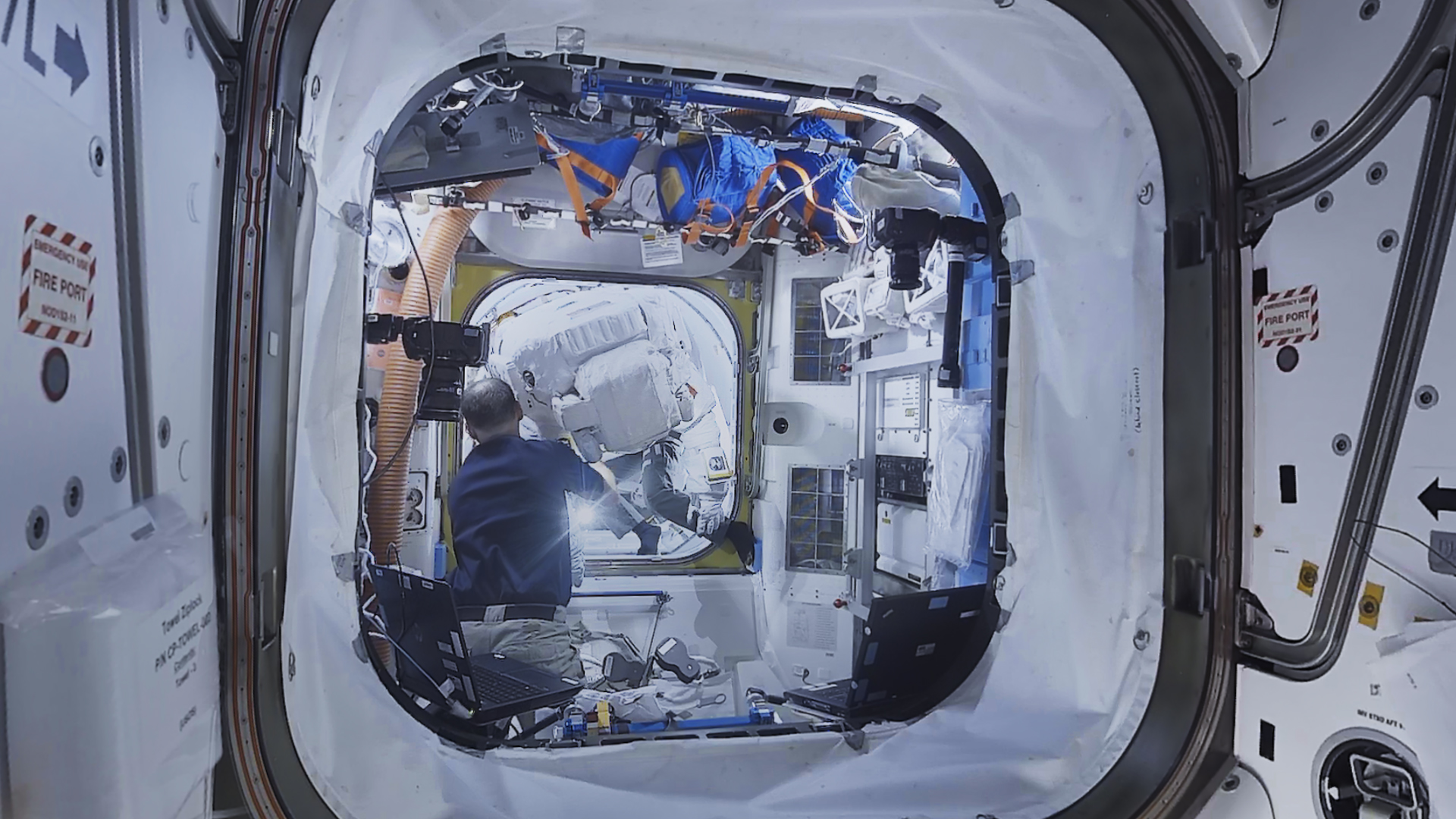 A photo of the interior of the ISS, showing a person within white walls.