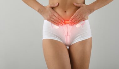 Young woman with drawing of reproductive system on light background. Gynecology concept