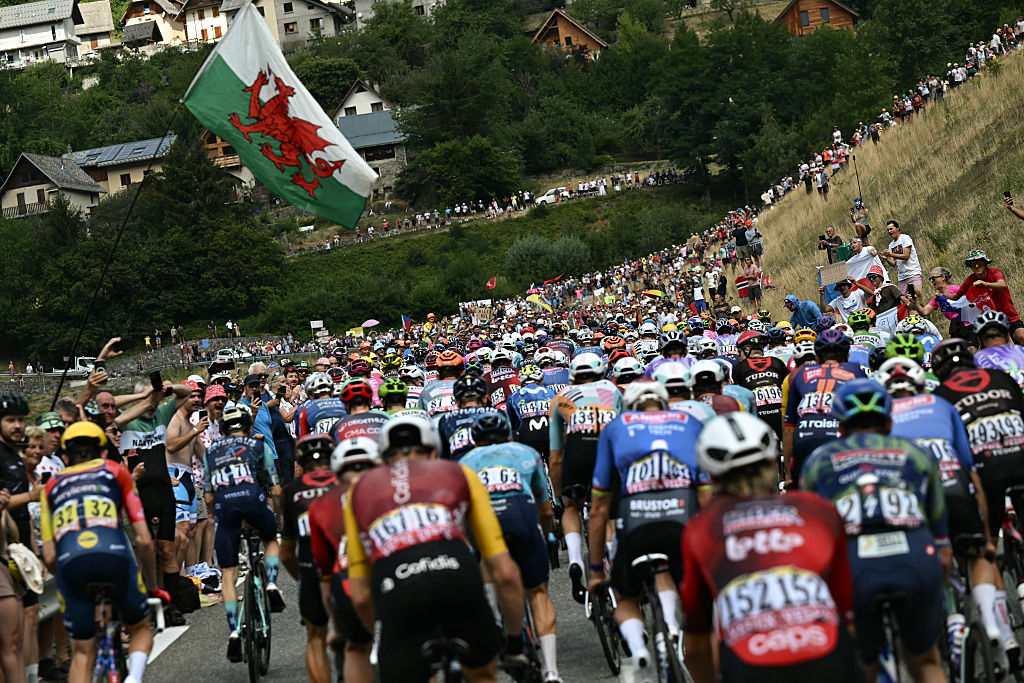 The pack of riders (peloton) cycles during the 20th stage of the 113th edition of the Tour de France cycling race, 170,9 km between Le Bourg-d'Oisans and Alpe d'Huez in the French Alps, on July 25, 2026. (Photo by Loic VENANCE / AFP)