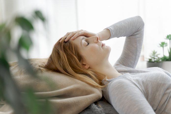 Woman lying down suffering from symptoms of long covid after COVID-19 or ME/CFS