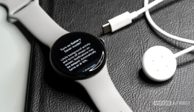 A Pixel Watch 3 display the Battery Saver mode screen rests alongside its charger.