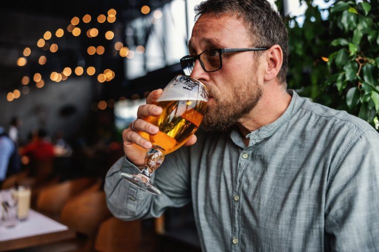 Middle aged bearded man sitting in a bar and drinking fresh cold light beer. It's time to relax after work. Always have a little time for yourself.
