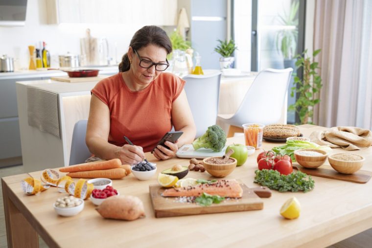 A woman adds up food calorie counts in her kitchen