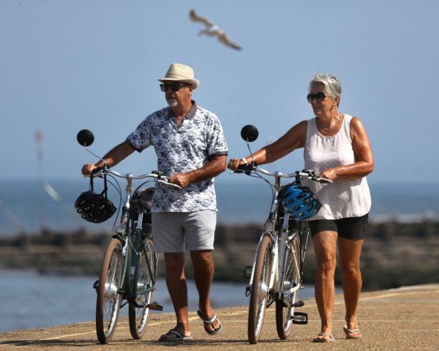 HUNSTANTON, ENGLAND - JULY 9: Cyclists push their bikes along the promenade in the early morning sun during a heatwave on July 9, 2029 in Hunstanton, England. The UK Health Security Agency (UKHSA) has issued yellow heat health alerts for the Midlands, East Anglia, London, and the south-east and south-west regions of England in effect through July 11, as temperatures are forecast to build into heatwave conditions. For some regions affected, the hot spell could mark the third official heatwave of the season, following record-breaking temperatures in May and June. (Photo by Martin Pope/Getty Images)