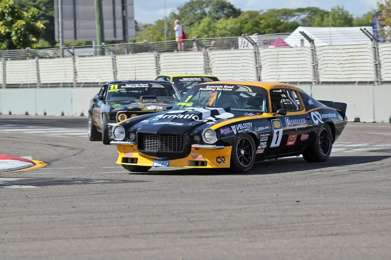 Joel Heinrich's black and yellow Chevrolet Camaro leads Angus Fogg's black and gold Ford Mustang and Ryan Hansford on the Townsville street circuit.