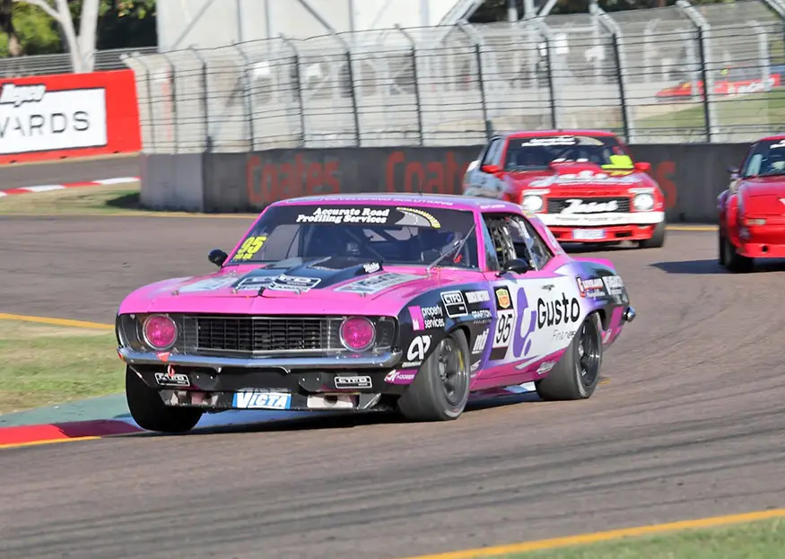 Scott Cameron's pink and purple #95 Whiteline Racing Chevrolet Camaro cornering on the Townsville street circuit.